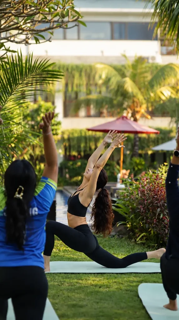 An instructor leading a yoga stretch on the garden lawn by the pool